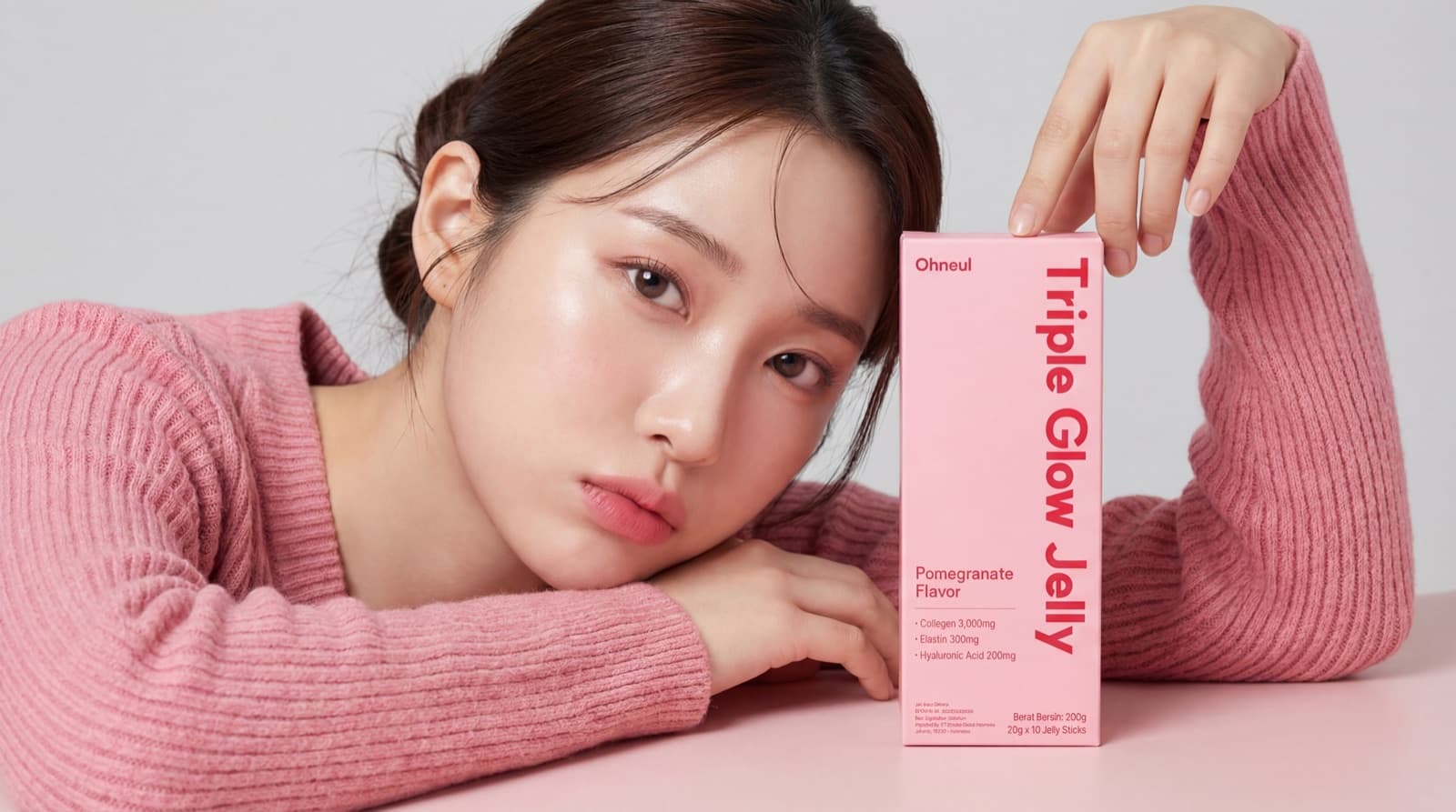A model in a pink sweater holding up a Triple Glow Jelly box